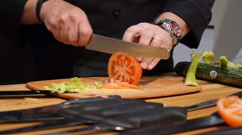 chef chopping a tomato with knife
