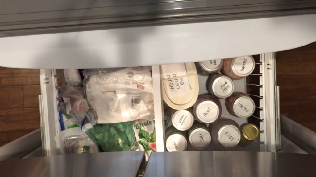 top shot of an open freezer drawer with lots of food stored in different types of containers 