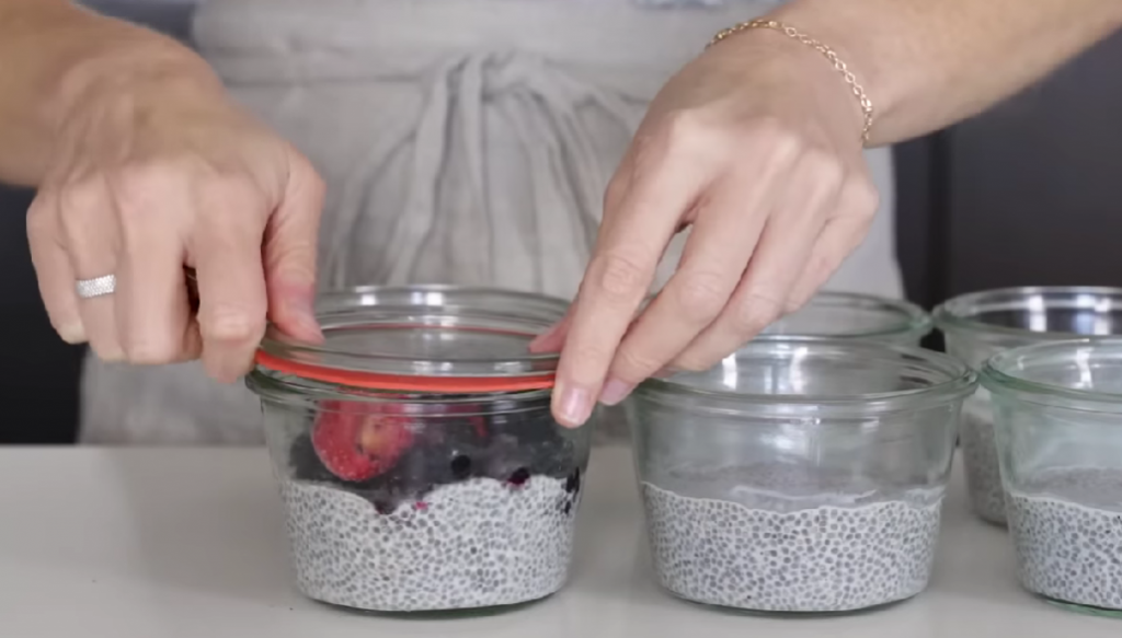 woman's hands sealing air tight plastic containers with chia pudding in it