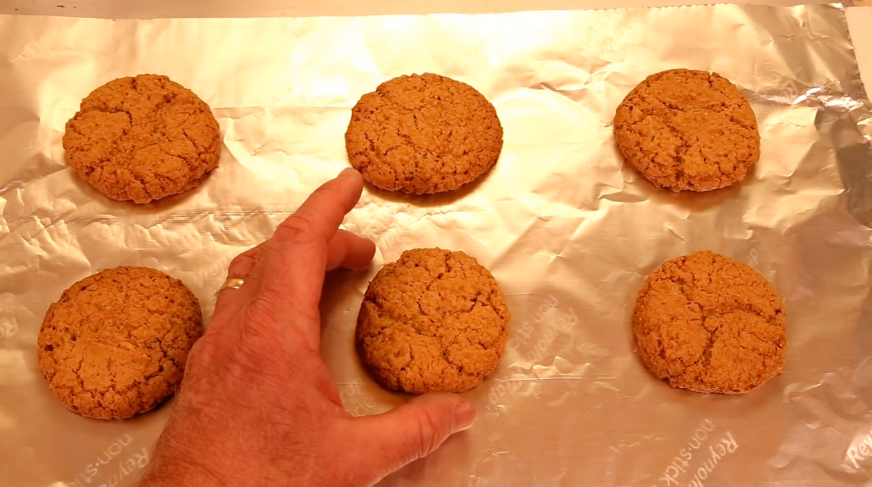 hand placing a sugar cookie on a Reynolds nonstick tin foil