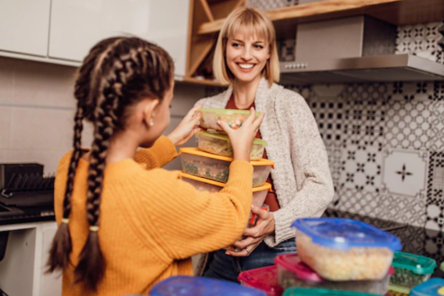 mother and daughter organizing Tupperware with food
